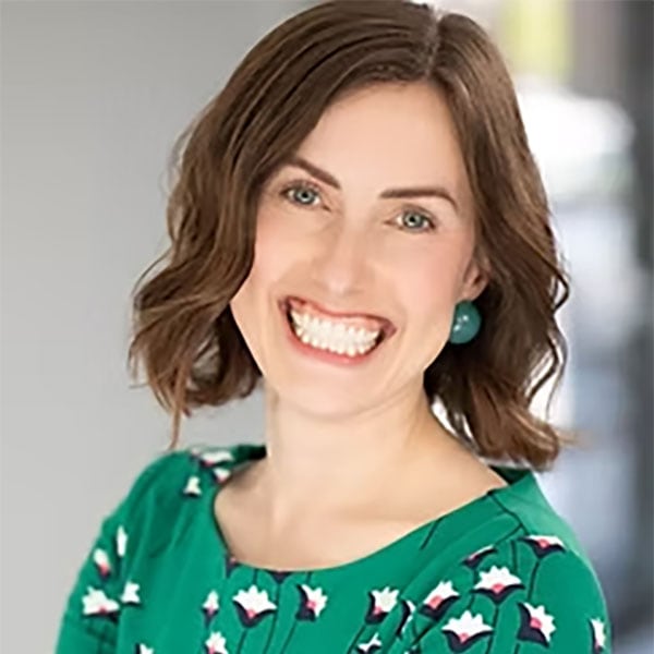 Smiling Woman In Professional Green Dress At Crescendo Consulting Office.